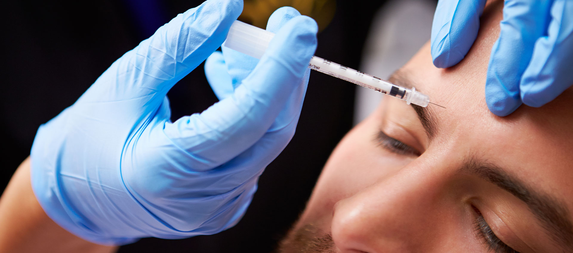 A person receiving a cosmetic treatment, with a syringe being used by a professional in front of them.