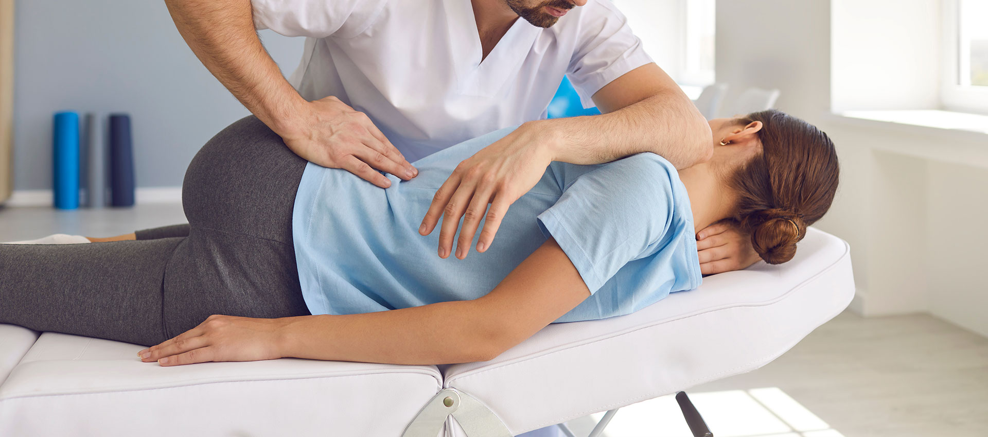 Physiotherapist performing a treatment on a patient, both in professional attire.