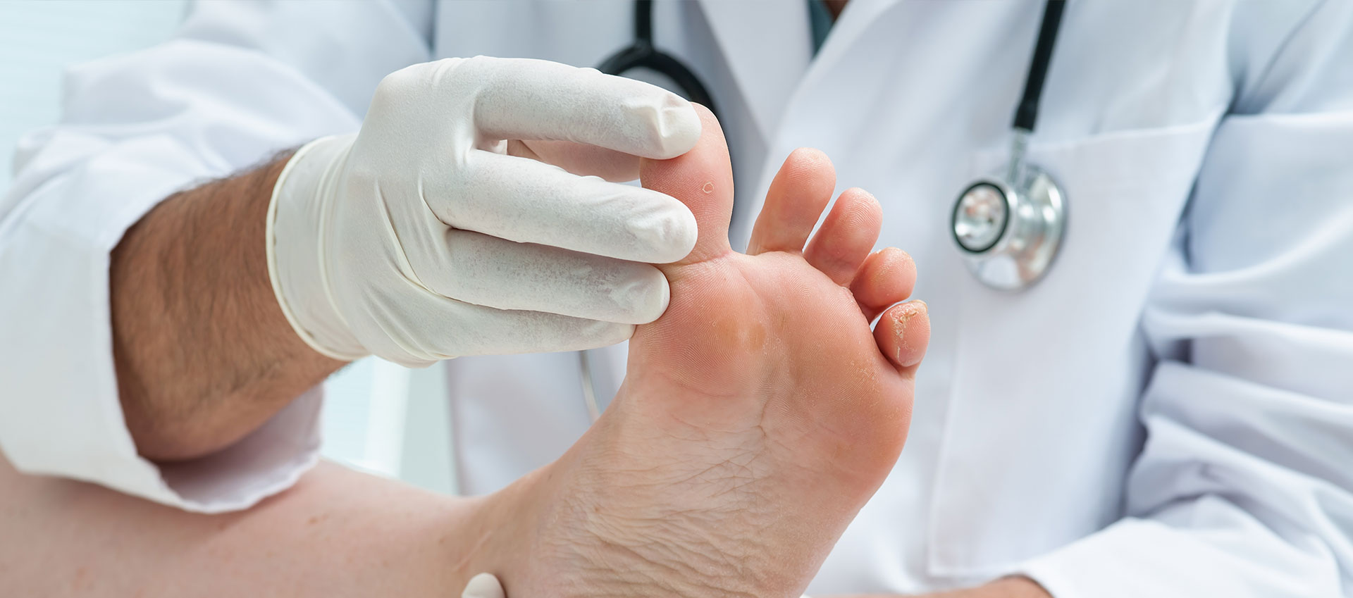 A medical professional wearing gloves is examining a person s foot.