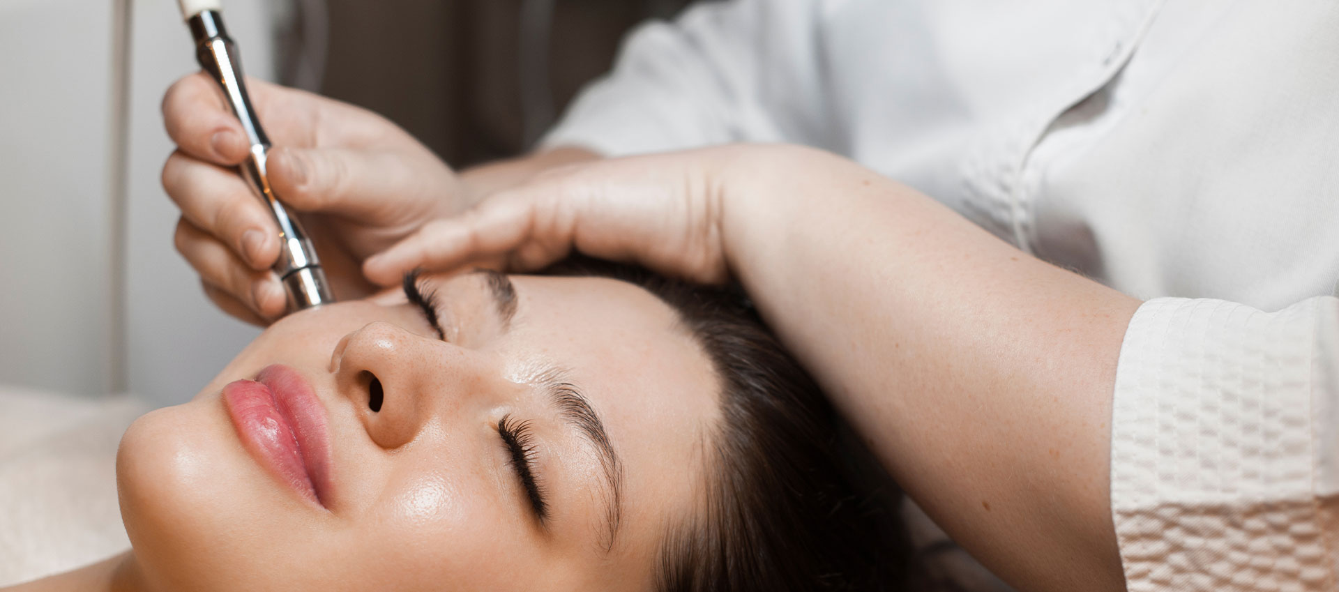 A person receiving a beauty treatment, with a focus on the process of applying makeup or skincare.