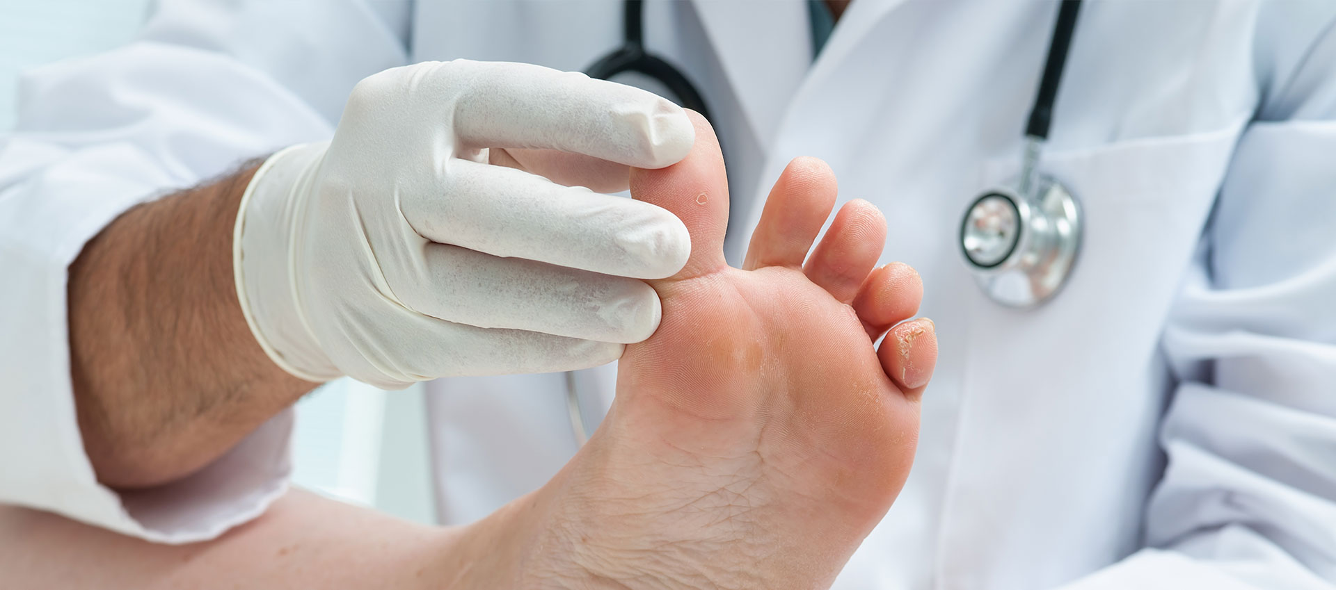 A medical professional is performing a foot examination on a patient s foot, with the patient s foot resting in the doctor s hand.