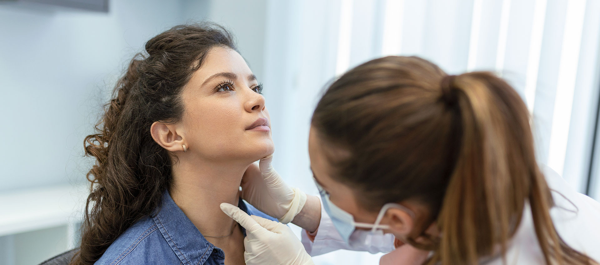 A woman in a dental office receiving treatment, with a female dentist examining her mouth.