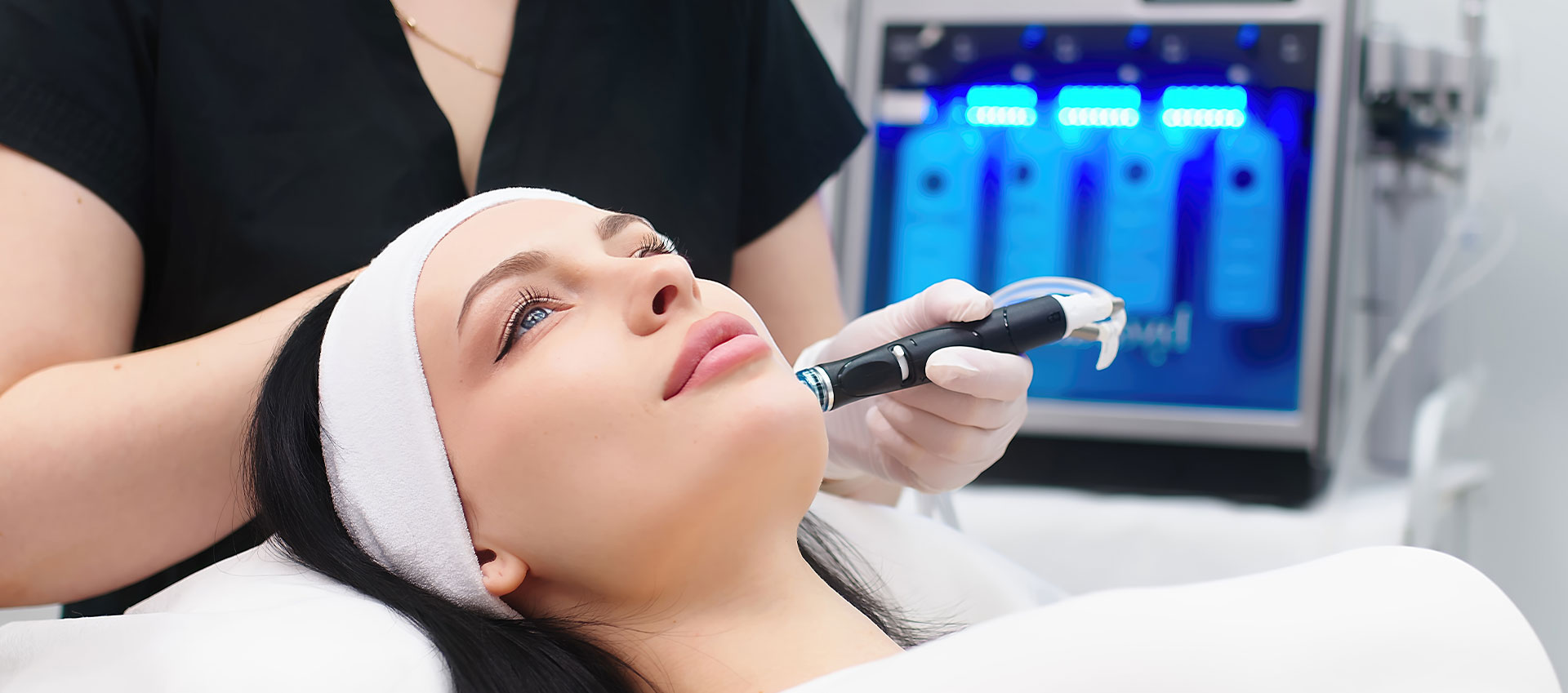 A person receiving a hair treatment in a salon, with a stylist using a device on their head.