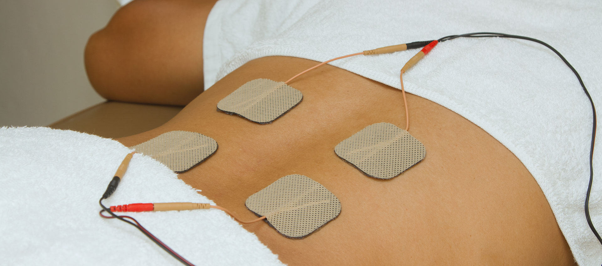 A person lying on a back table with electrodes attached to their skin.