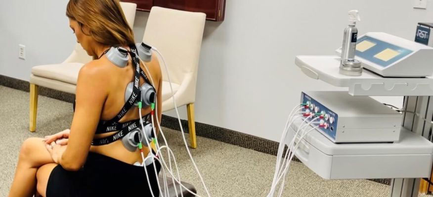 An image of a person seated in a chiropractic adjustment chair with their back exposed, receiving treatment or examination.