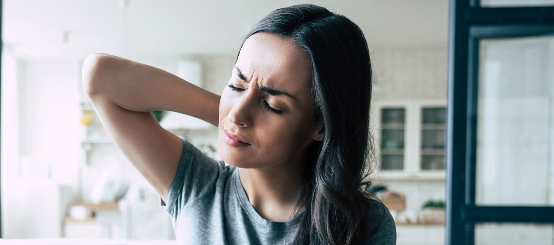 A woman with her hand on her head, appearing to be in pain or discomfort.