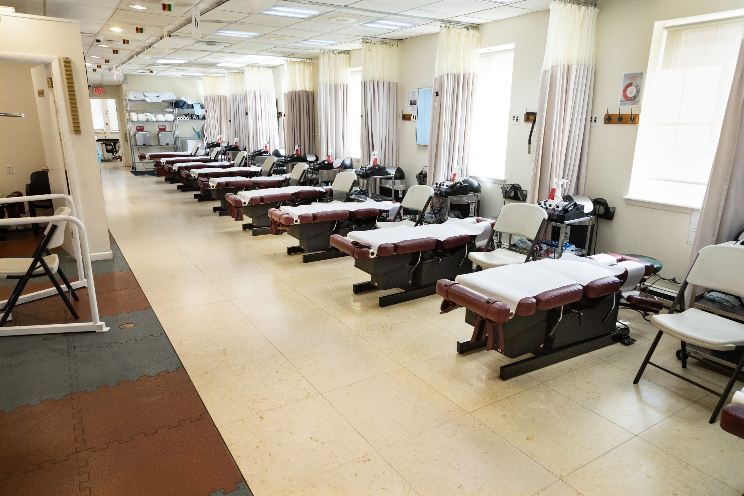 An image depicting a well-lit room with multiple massage tables, indicating it's a massage therapy or spa setting.