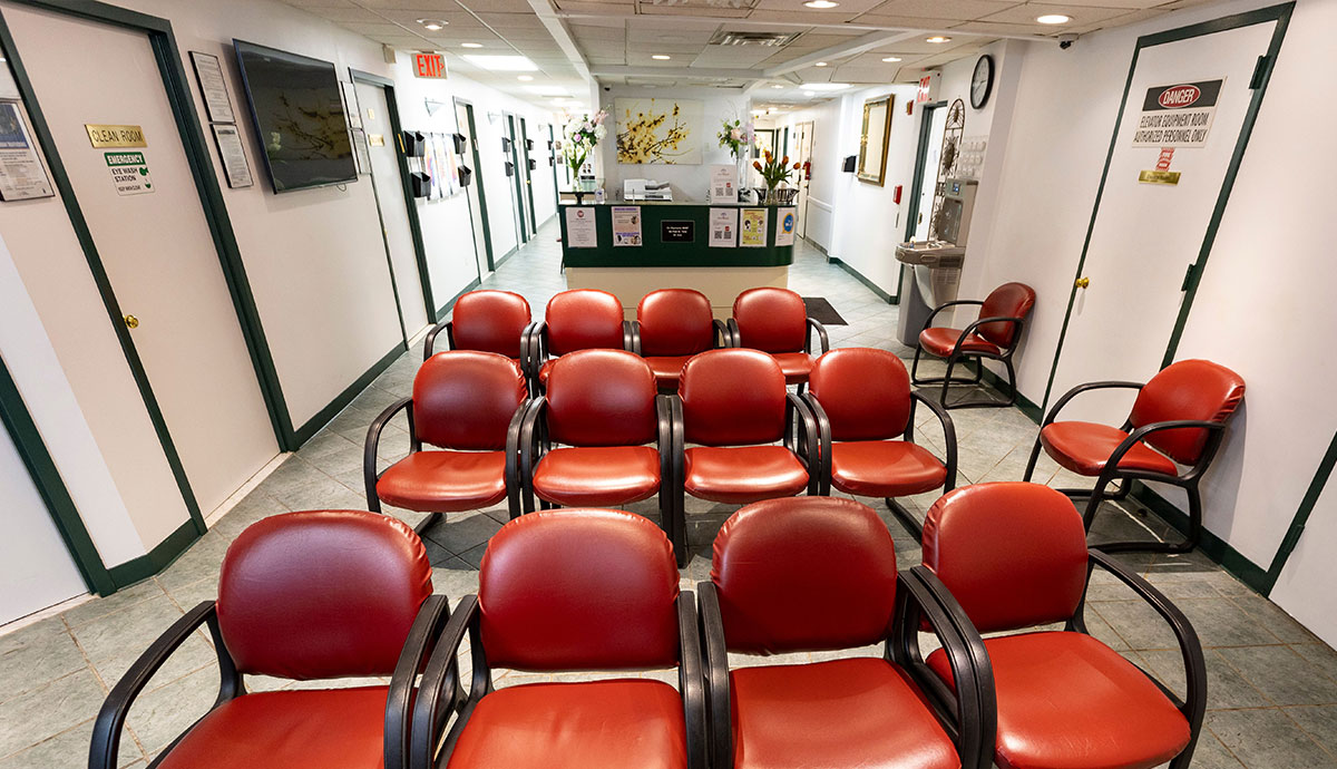 The image shows an interior space, specifically a waiting area with several red chairs arranged in rows facing the same direction.